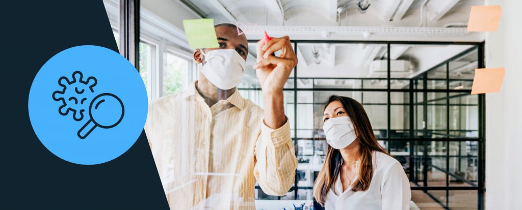 two people working in front of whiteboard in face masks